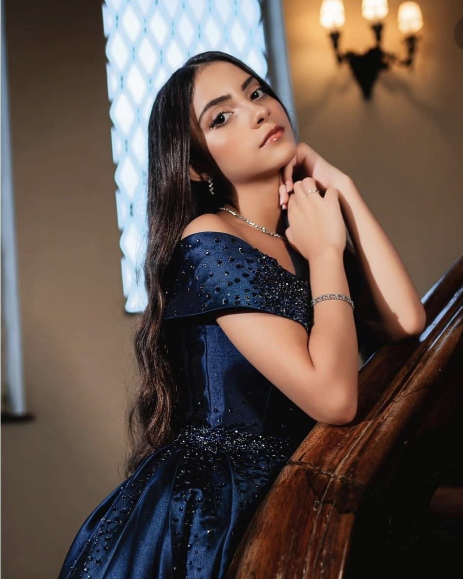 Debutante em vestido azul-marinho bordado, com cabelo solto ondulado