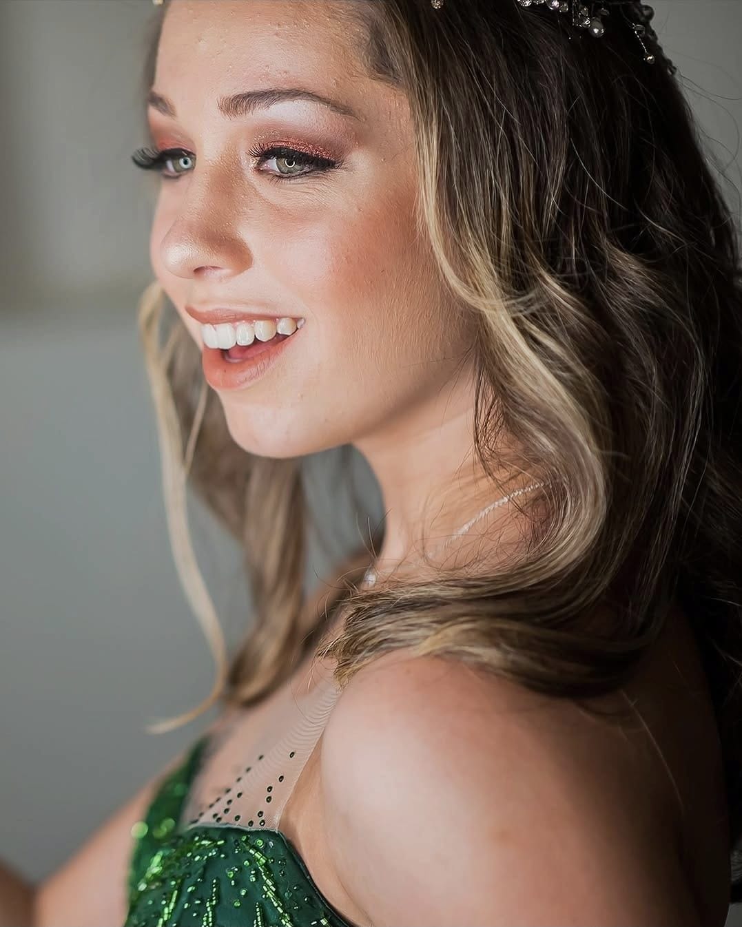Debutante em vestido verde, com tiara e maquiagem em tons de rosa